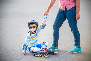 Preschooler falls over while rollerblading with mother in the park