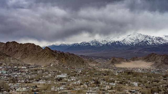 4K Timelapse of cityscape and high snow mountain range on rural desert landscape and Leh Palace with beautiful blue cloudy sky and amaizing cloud moving as background, viewed of rooftop Leh, India.