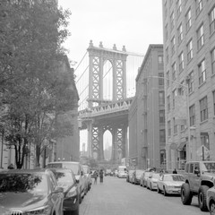 Empire State Building framed by the Legs of the Manhattan bridge in New York City. Scanned black and white film photo. Captured with a medium format SLR camera from 1960s.
