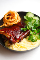 baked barbecue ribs with mashed potatoes in a cast iron pan