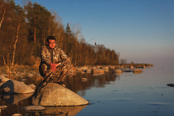 Man catches fish standing on stones in water