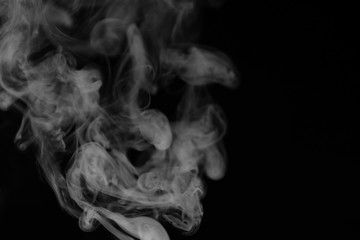 White smoke on a black background. Texture of smoke. Clubs of white smoke on a dark background for an overlay