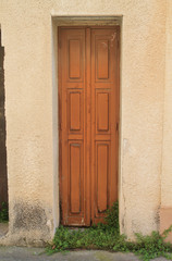 narrow wooden brown door with wildflowers