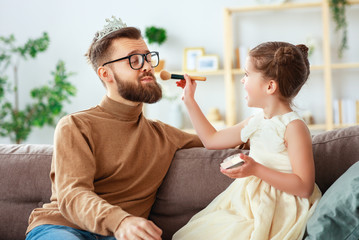 happy father's day! child daughter in crown does makeup to daddy.