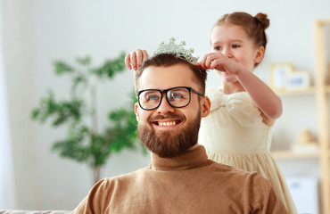 happy father's day! child daughter in crown does makeup to daddy.