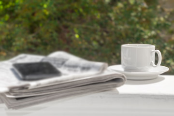 The concept of news. Newspaper, a Cup of morning coffee on the background of the summer Park.