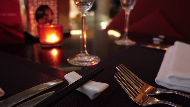 Place setting at upscale Chinese restaurant. Table setup at Oriental western hotel. Utensils including chopsticks and wine glasses at dimly lit Asian restaurant. Romantic, expensive Chinese dinner.