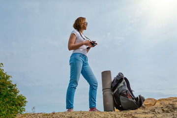 A young woman travels with a backpack and decided to take some photos in a beautiful place. Sky with sun on the backround