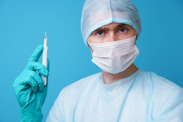 Surgeon in sterile blue uniform, medical gloves and mask