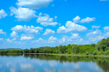 river with a green bank and clouds