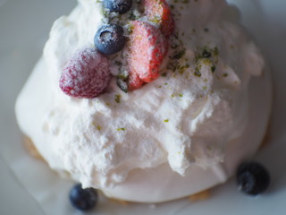 blurred Pavlova cakes with cream and fresh summer berries, soft mist