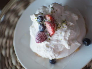 blurred Pavlova cakes with cream and fresh summer berries, soft mist
