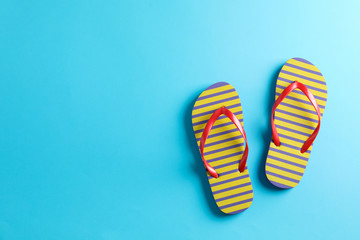 Flip flops on color background, space for text. Summer vacation backdrop