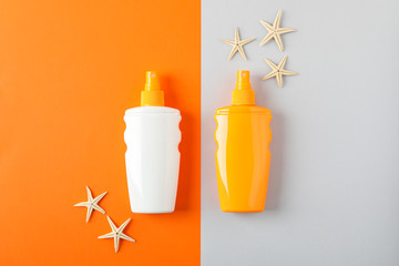 Flat lay composition with sunscreen sprays and starfishes on two tone background, space for text....