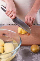 young woman in an apron cuts potatoes