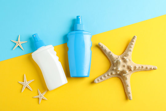 Flat lay composition with sunscreen sprays and starfishes on two tone background, space for text. Summer vacation backdrop