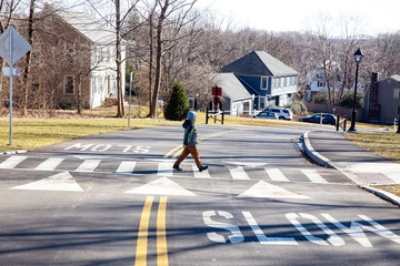 kid walking on crosswalk.boy goes across the road in front of the car