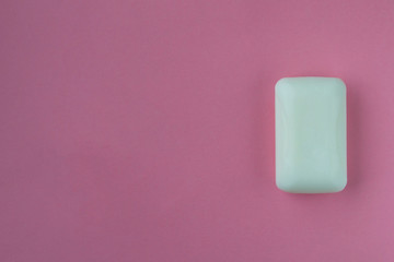 A bar of white soap on a pink background.
