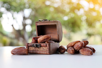 Ramadan concept. dry dates in classic wooden box on white wooden table. fresh green background.