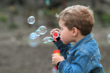 The boy in the denim jacket blows bubbles