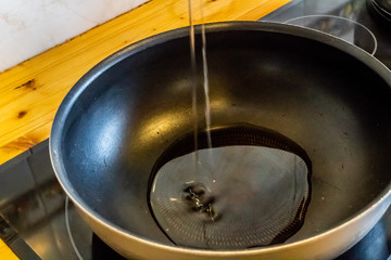 pouring olive oil from Spain, in a black pan