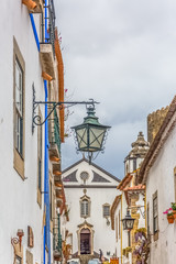Fototapeta na wymiar View of a traditional street lamp, Portuguese vernacular buildings on medieval village inside the fortress and Luso Roman castle of Óbidos, in Portugal