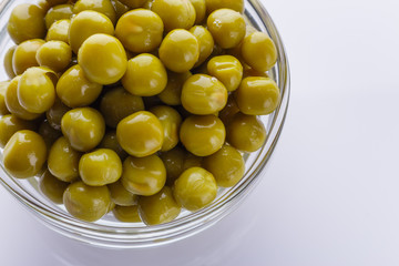canned green peas in a glass bowl on a white background