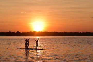 Silhouette of the young women doing yoga on sup board with paddle, Gili Trawangan Island, Indonesia