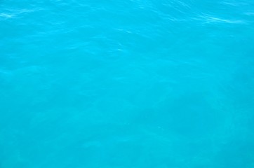 Panoramic background with ripples on water, close up. Sea water surface in sunlight. Beautiful clear blue water background.