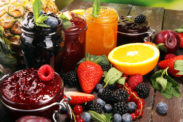 assortment of jams, seasonal berries, plums, mint and fruits in glass jar