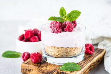 No baked cheesecake with raspberry in glass jar.