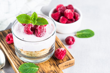 No baked cheesecake with raspberry in glass jar.