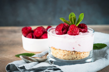 No baked cheesecake with raspberry in glass jar.