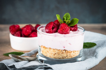 No baked cheesecake with raspberry in glass jar.