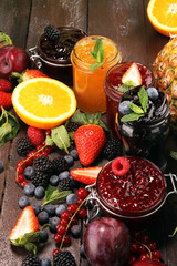 assortment of jams, seasonal berries, plums, mint and fruits in glass jar