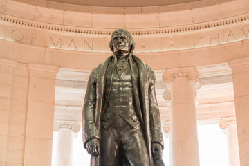 Bronze statue of Thomas Jefferson in Jefferson Memorial in Washington DC as setting sun illuminates...