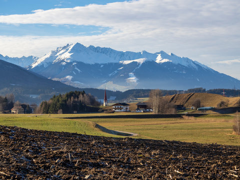 Paisaje Austriaco  , con campo, una iglesia y al fondo monta&ntilde;as nevadas por la zona de Igls en Innsbruck, invierno de 2018