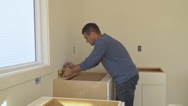 Installing cabinets in a kitchen of dark color in the process of completing the kitchen installation