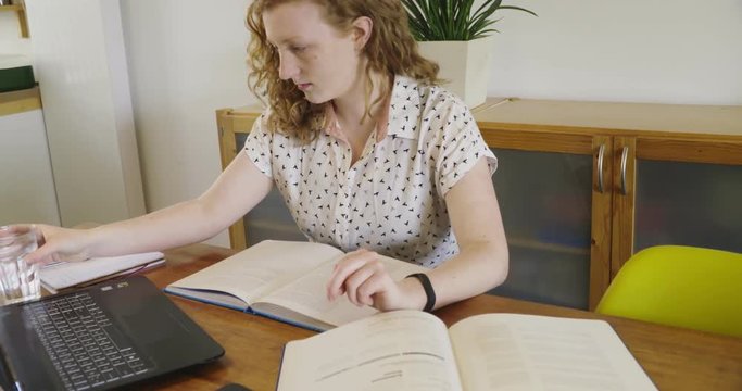 Young studen, blonde woman studying and working behind laptop, with books and notepad