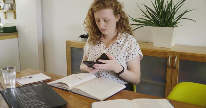 Young studen, blonde woman studying and working behind laptop, with books and notepad