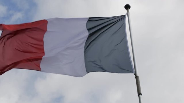 Flag of France waving in the wind against the blue sky. Slow Motion.
