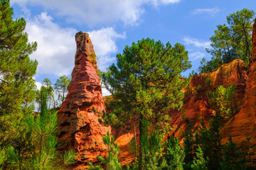 Roussillon ochre deposit: Beautiful big red ocher peak, blue sky and green pines.