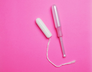 Woman Hygienic tampons with applicator on pink backdrop surface.