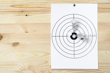 Four medical syringe hit the center of the rifle target. On the wooden background. Humor concept of therapy.