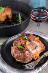 Roasted red meat and a glass of wine on the table. A hearty lunch with alcohol. Vertical format.