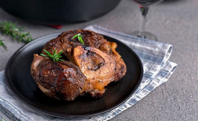 A large piece of fried meat on the bone in a plate and a glass of red wine. Served table for high-calorie lunch.