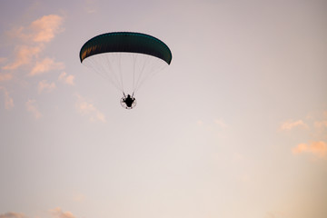 Paramotor silhouette flying on sky at sunset. Adventure, extreme sport and active life concept