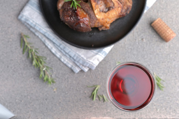 A large piece of fried meat on the bone in a plate and a glass of red wine. Served table for high-calorie lunch.