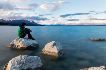 Man sitting on a rock looking out over lake Pukaki