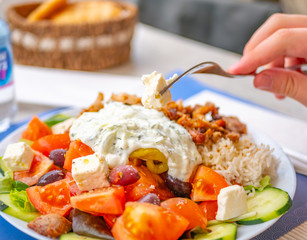 Close up of tomatoes, olives, feta cheese and slices of cucumbers from a famous Greek salad, against a blurred background